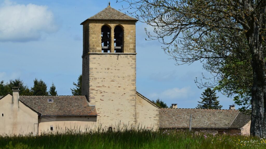 Clocher en pierre d'une église de village dans un paysage rural français