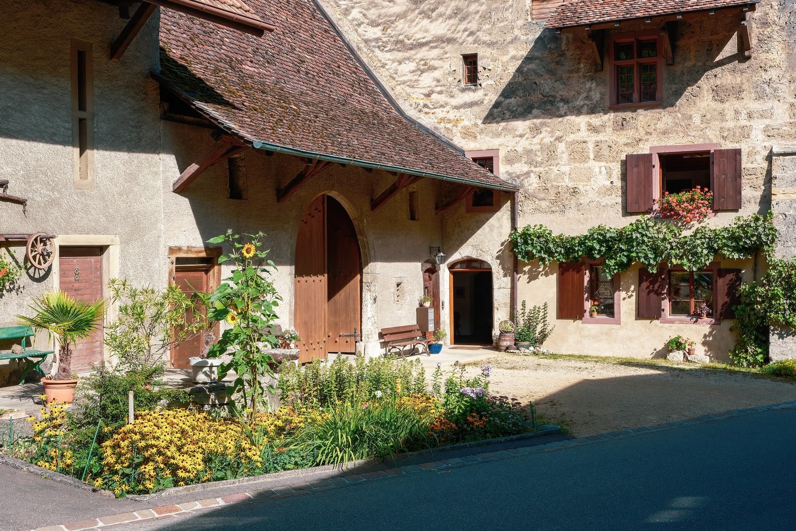 Cour fleurie d'une ferme en pierre à la campagne