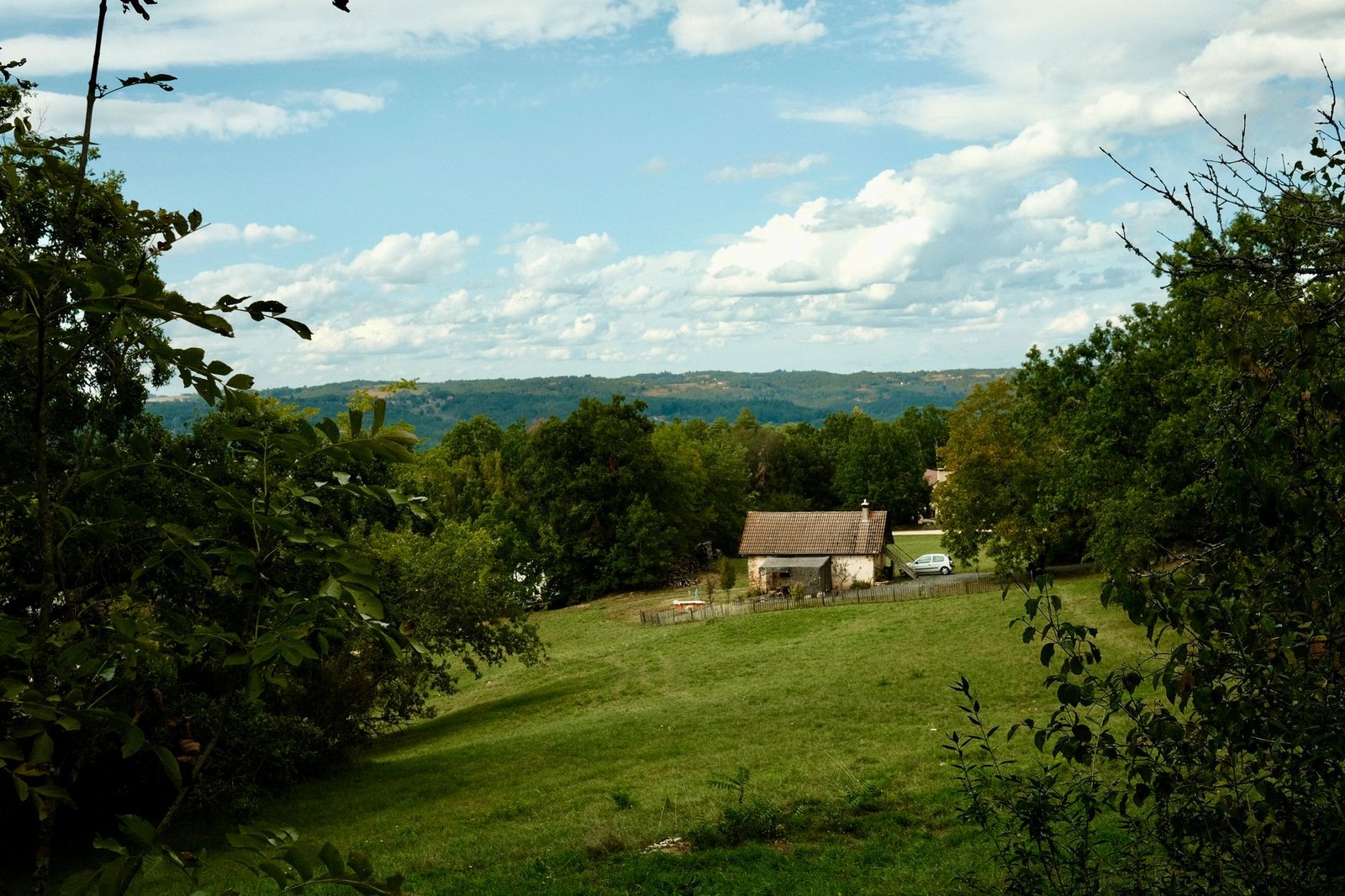Maison de campagne en pierre au milieu d'un pré, lisière de forêt