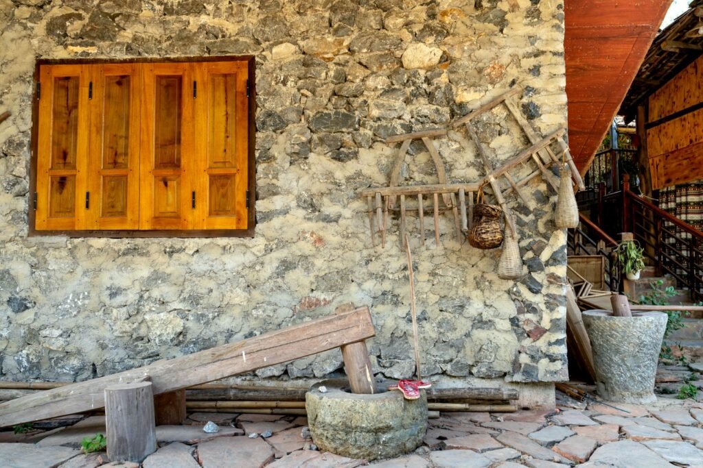 Mur en pierre d'une vieille maison de campagne avec volets de bois et outils anciens