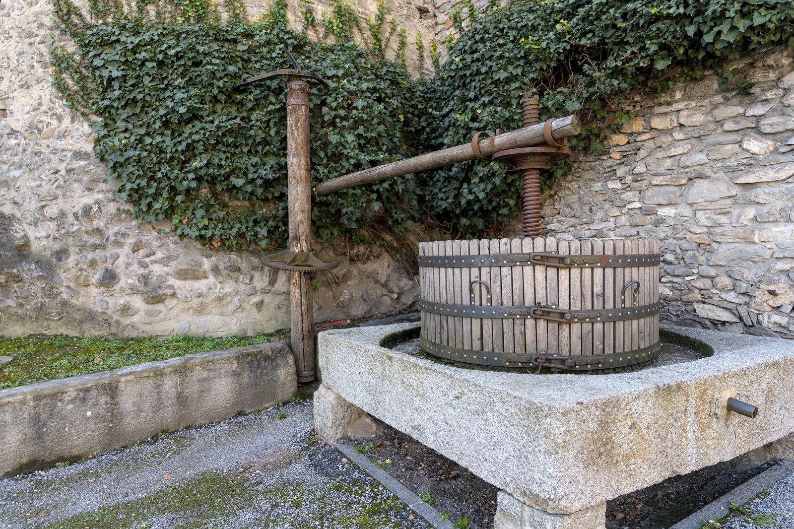 Ancien pressoir en bois massif contre un mur de pierre